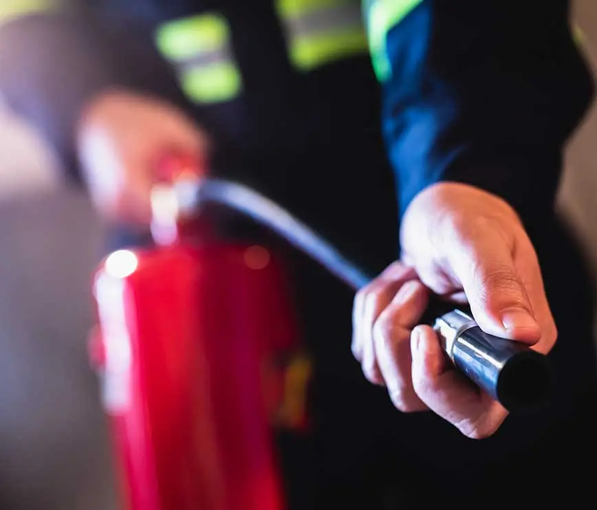 Feuerlöscher in Gebrauch – Person hält Löschschlauch bereit für den schnellen Einsatz bei Bränden.